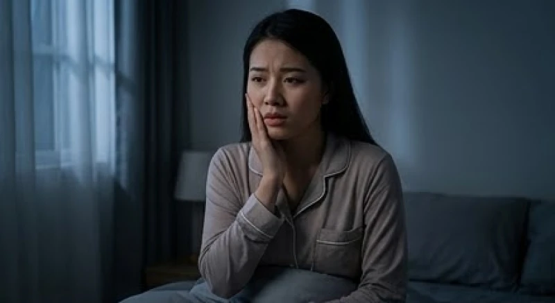 Biểu cảm lo âu của người phụ nữ vừa thức giấc sau giấc mơ thấy gãy răng chảy máu