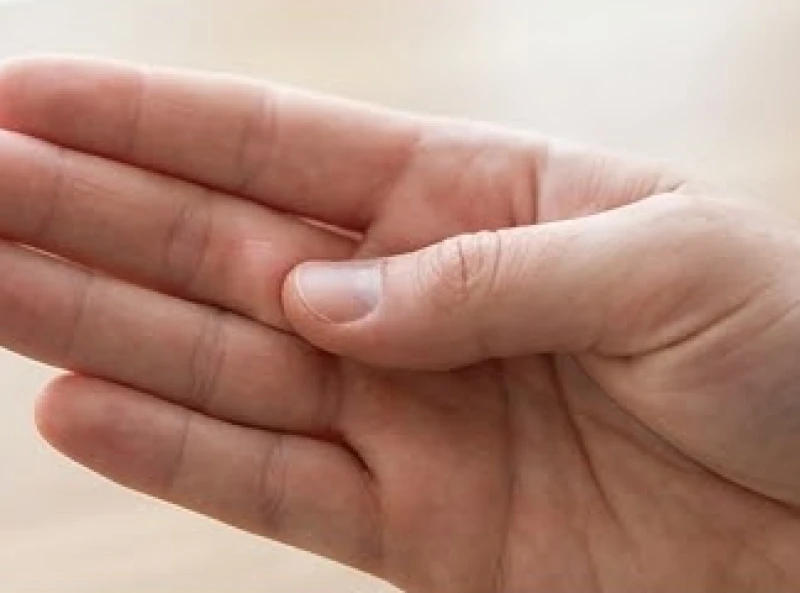 Ngón cái của bàn tay kia đang ấn nhẹ vào một gò đệm thịt trên lòng bàn tay để kiểm tra độ đàn hồi.