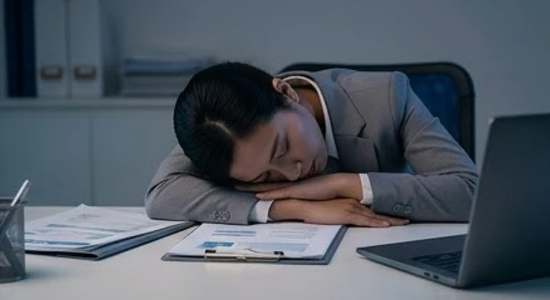 Nữ nhân viên mệt mỏi gục đầu trên bàn làm việc đầy giấy tờ vào ban đêm