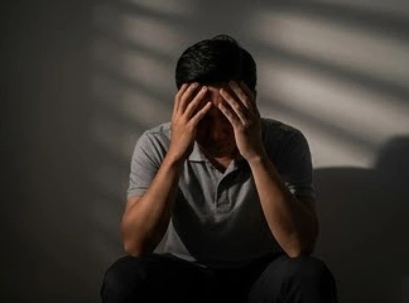 Người đàn ông ngồi gục đầu trong bóng tối lo âu về những bí mật có thể bị bại lộ sau giấc mơ