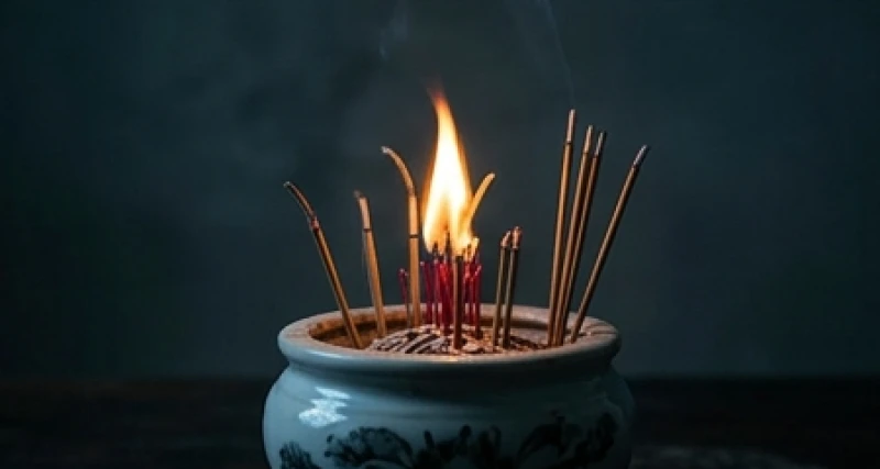 Bát hương cắm đầy chân nhang đang bùng lên ngọn lửa nhỏ giữa không gian mờ tối