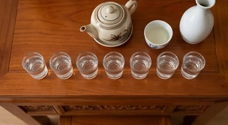 Bảy ly nước suối trong vắt cùng bình trà và rượu trắng được sắp xếp cẩn thận trên án thờ