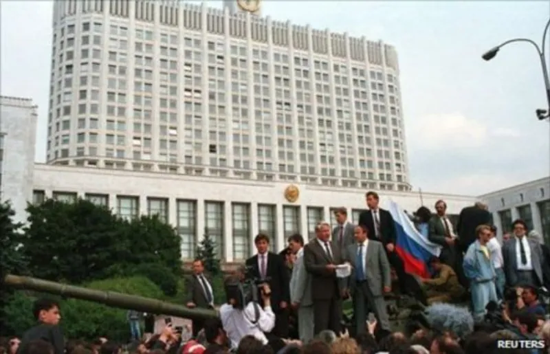 Boris Yeltsin đứng trên một chiếc xe tăng, tay giơ cao, nói chuyện với đám đông.