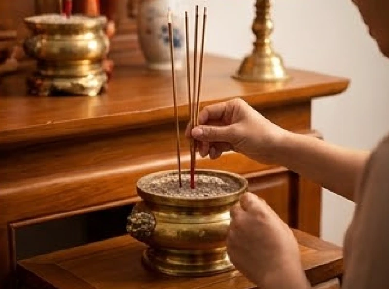 Gia chủ chắp hai tay cắm nhang thẳng đứng vào bát hương trên bàn thờ gia tiên