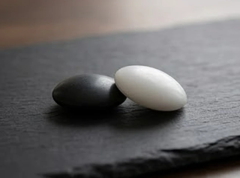 Sim phong thủy tuổi Tỵ: Tự tính tỷ lệ chẵn lẻ và ngũ hành 4 Hai hạt cờ vây trắng đen đặt cân bằng hoàn hảo trên một phiến đá phiến