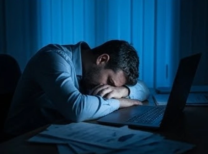 Người nhân viên gục đầu xuống bàn làm việc giữa đêm khuya giải thích nguyên nhân tâm lý gây ra mơ thấy cá sấu cắn