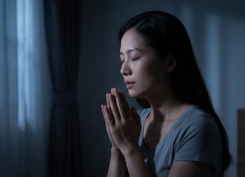 Người phụ nữ thành tâm nhắm mắt chắp tay cầu bình an dưới tia sáng trăng mờ ảo