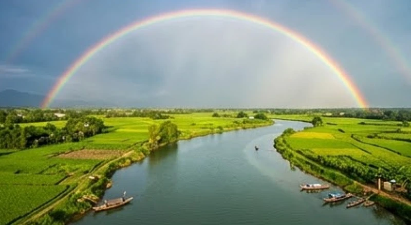Cầu vồng là điềm gì: Giải mã phong thủy và điềm báo giấc mơ 3 Cầu vồng lớn vắt ngang qua một dòng sông rộng bao quanh bởi khung cảnh nông nghiệp trù phú