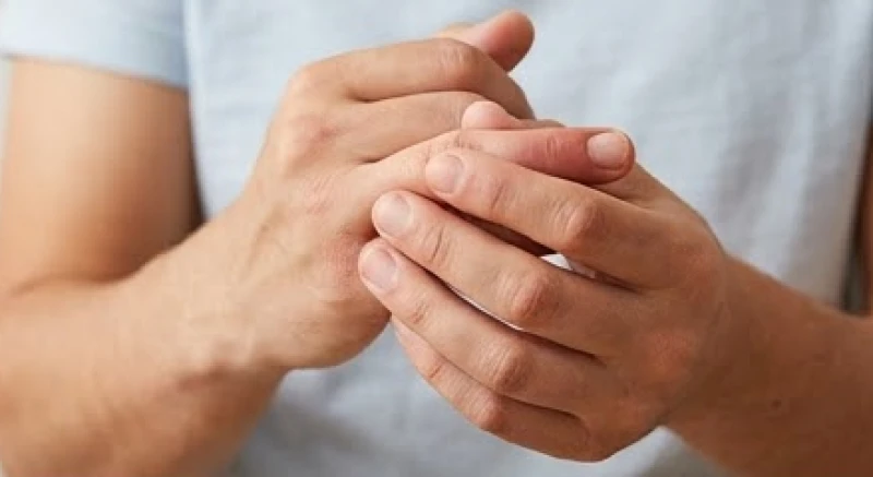 Bàn tay nam giới đang xoa bóp khớp ngón trỏ bị sưng đỏ sau tổn thương do va đập hoặc bẻ khớp liên tục
