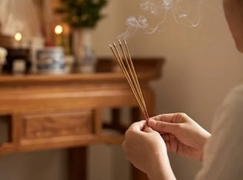 Gia chủ thành tâm chắp tay cầm nén nhang trầm đang cháy vái lạy trước bàn thờ thần linh tại nhà mới