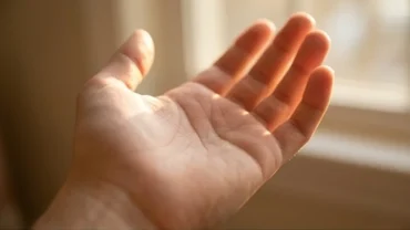 Bàn tay úp nghiêng dưới ánh sáng làm nổi bật các đặc điểm của chỉ tay kết hôn muộn