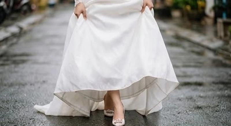 Trời mưa trong ngày cưới là điềm gì: Ý nghĩa và mẹo ứng phó 5 Cô dâu khéo léo nâng nhẹ gấu váy cưới bước đi dưới sự che chở của chiếc ô trong suốt để tránh bùn đất