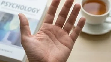Bàn tay mở rõ đường nét bên cạnh tách trà, giải đáp việc có nên tin vào đường chỉ tay không dưới góc độ khoa học