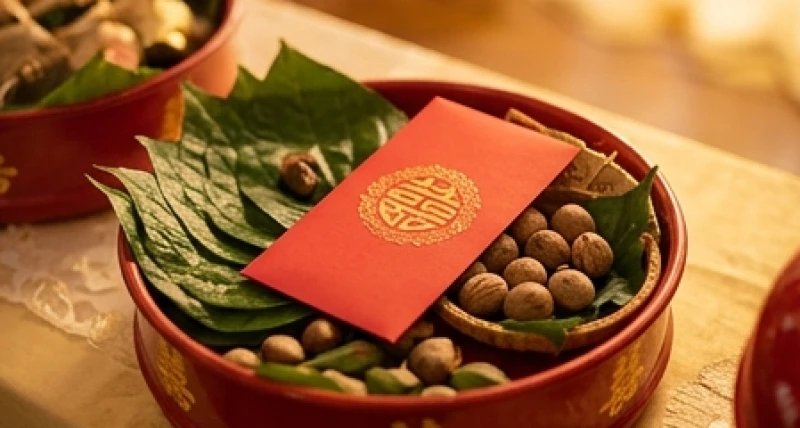 Chiếc phong bao lì xì màu đỏ được đặt trang trọng bên cạnh tráp cưới truyền thống đại diện cho điềm lành