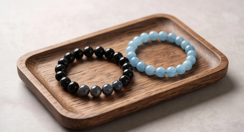 Vòng tay đá phong thủy thạch anh đen và ngọc aquamarine màu xanh lam đặt trang trọng trên đĩa gỗ