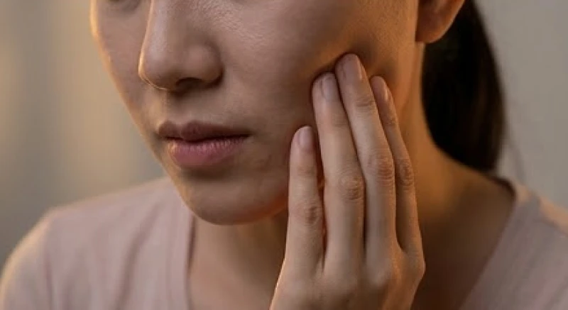 Bệnh nhân nhăn nhó ôm má vì cơn đau nhức răng ê buốt kéo dài trong đêm
