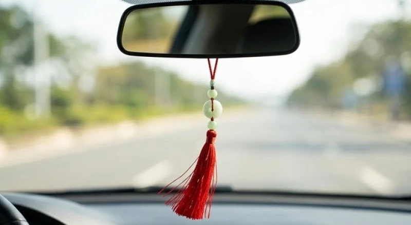 Dây khánh bình an màu đỏ với chuỗi hạt được treo cân đối trên gương chiếu hậu ô tô