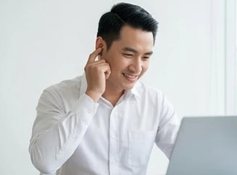 Ù tai là điềm gì: Tra cứu theo giờ và góc nhìn y khoa 3 Nam thanh niên mặc sơ mi công sở đang chạm vào tai trái khi nhận được tin vui về công việc