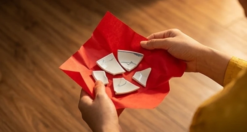 Tuổi Thân kiêng gì trong ngày Tết: chi tiết theo 5 nạp âm 6 Đôi bàn tay cẩn thận bọc những mảnh vỡ của chiếc bát sứ trắng vào trong một tờ giấy màu đỏ sẫm