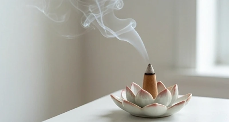 Làn khói trắng mỏng manh tỏa ra từ nụ trầm hương đang cháy êm đềm trên đài sen gốm sứ tinh xảo