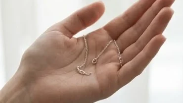 Sợi dây chuyền bạc đứt nằm gọn trong lòng bàn tay người phụ nữ đang tìm hiểu đứt dây chuyền bạc là điềm gì