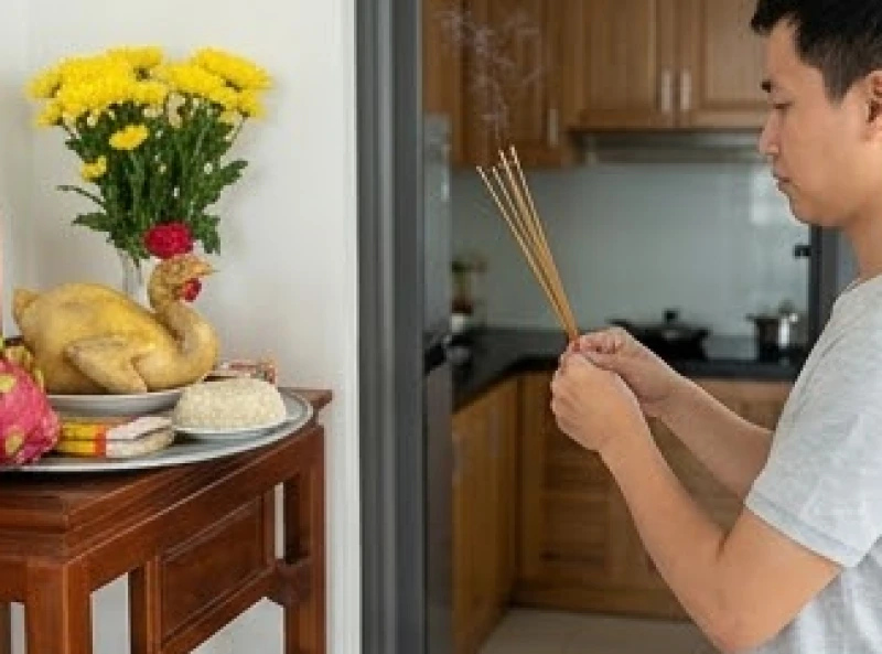 Người đàn ông thắp hương tại mâm lễ cúng sửa bếp được đặt trang trọng trước cửa không gian nấu nướng