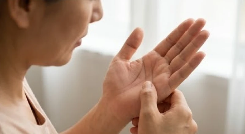 Người phụ nữ đang tập trung quan sát đường sinh mệnh ngắn trên lòng bàn tay trái của mình