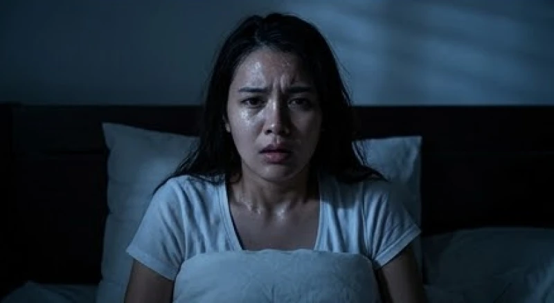 Một người choàng tỉnh giữa đêm với vẻ mặt lo âu và đổ mồ hôi do áp lực công việc ban ngày quá lớn