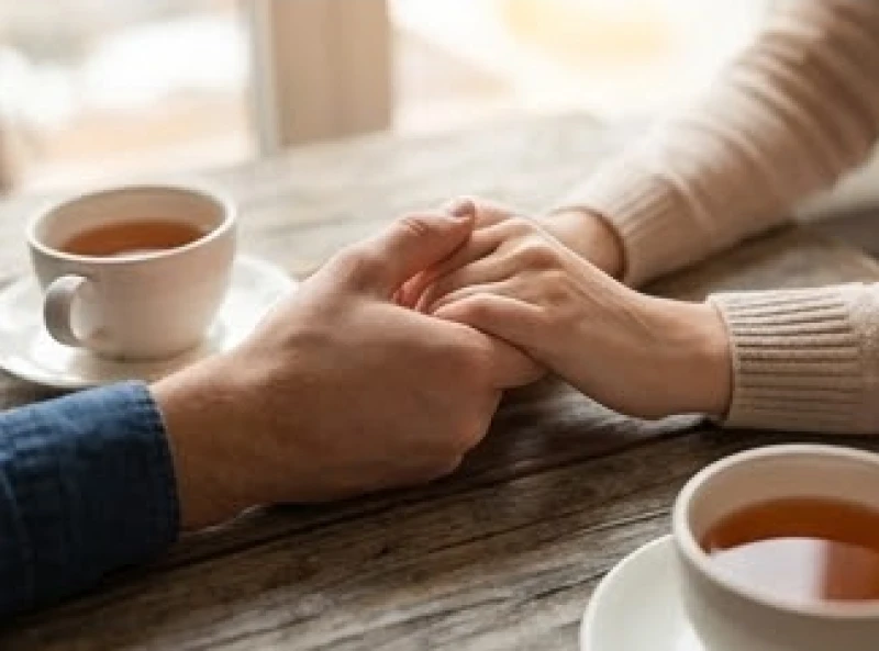 Hai vợ chồng nắm tay nhau bên tách trà ấm để vượt qua giai đoạn đường hôn nhân rẽ nhánh