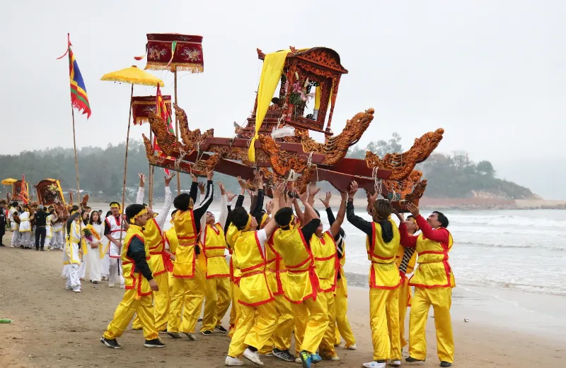 Hình ảnh minh họa lễ hội chạy ói với đám đông người dân chen chúc nhau, khiêng kiệu và chạy trên bãi biển cát trắng, tạo nên một không khí náo nhiệt, sôi động.