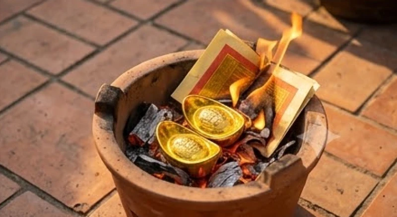 Gia chủ đang cẩn thận hóa vàng mã trong một chiếc thố gốm chịu nhiệt tại khoảng sân thoáng đãng