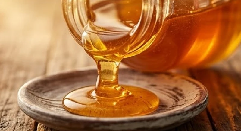Mật ong vàng óng dâng cao và tràn nhẹ ra khỏi miệng hũ thủy tinh trong suốt, thể hiện sự dư dả về tài lộc