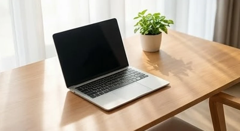 Bàn làm việc bằng gỗ được sắp xếp gọn gàng với laptop mở sẵn đón luồng sinh khí từ cửa sổ