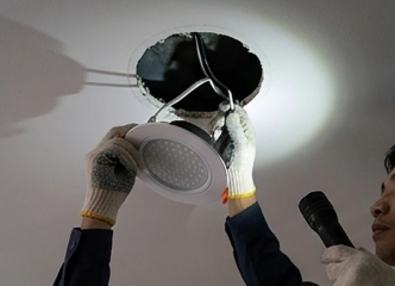 Thợ điện tháo bóng đèn downlight để kiểm tra đường dây bị chuột cắn gây chớp nháy và có mùi khét