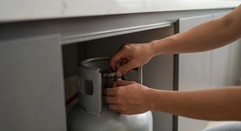 Hành động cẩn thận khóa van an toàn của bình ga dưới khu vực bếp nấu hiện đại để ngăn ngừa sự cố
