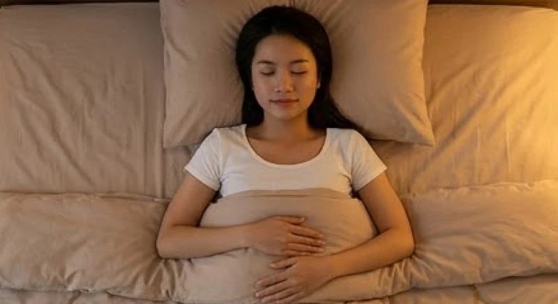 Cách để không gặp ác mộng: Vệ sinh giấc ngủ và xử lý tức thì 7 Người phụ nữ nằm nhắm mắt thư giãn và đặt tay lên bụng để thực hiện bài tập hít thở sâu ngay tại giường
