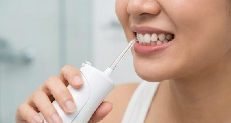 Bước làm sạch mảng bám sâu kẽ răng khểnh bằng tia nước áp lực cao từ máy tăm nước
