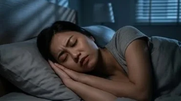Người phụ nữ đang ngủ say trên giường và cau mày lo lắng khi mơ thấy bị trộm cướp đột nhập vào nhà