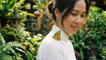 Cánh bướm vàng đậu trên vai cô gái mặc áo dài tại Hội An Việt Nam, gợi mở điềm lành khi mơ thấy bướm đậu vào người