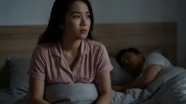 Người phụ nữ Việt Nam trằn trọc thức giấc trên giường với vẻ mặt âu lo khi mơ thấy chồng ân ái với người khác