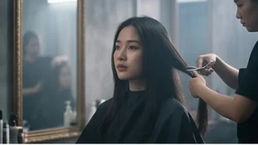 Cô gái trẻ đang suy ngẫm khi thợ làm tóc cắt đi mái tóc dài tượng trưng cho giấc mơ thấy đi cắt tóc
