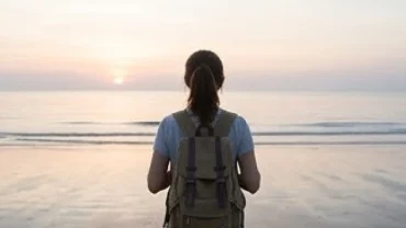 Người phụ nữ khoác balo ngắm bình minh trên biển, đại diện cho điềm báo tốt lành khi mơ thấy đi du lịch