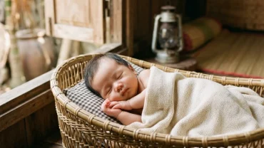 Em bé trai sơ sinh đáng yêu mỉm cười trong nôi gỗ gợi nhắc điềm báo tích cực từ giấc mơ thấy em bé trai sơ sinh