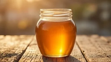 Chiếc hũ chứa đầy mật ong vàng óng rực rỡ dưới nắng phản ánh điềm báo tài lộc dồi dào khi bạn mơ thấy hũ mật ong