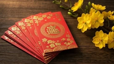 Phong bao lì xì đỏ rực rỡ trên cành mai vàng tượng trưng cho giấc mơ thấy mừng tuổi đầy may mắn và tài lộc