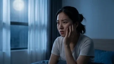Người phụ nữ lo lắng chạm tay vào má khi tỉnh dậy sau giấc mơ thấy răng sâu bị rụng trong đêm