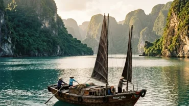 Con thuyền gỗ truyền thống lướt trên mặt biển bình minh tĩnh lặng tượng trưng cho điềm báo khi mơ thấy thuyền và biển