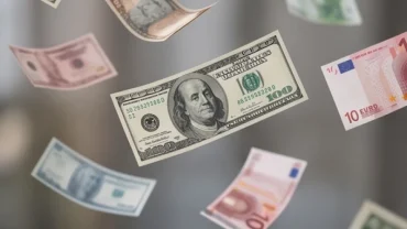 Các tờ ngoại tệ Đô la Mỹ và Euro bay lơ lửng trong ánh sáng nhẹ đại diện cho giấc mơ thấy tiền nước ngoài