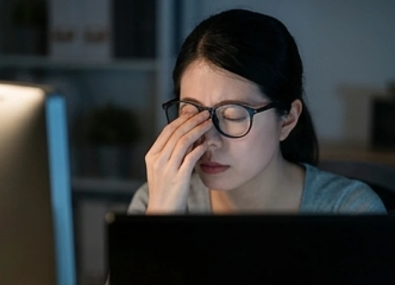 Nhân viên văn phòng nheo mắt khó chịu khi làm việc quá lâu trước màn hình máy tính phát ra ánh sáng xanh