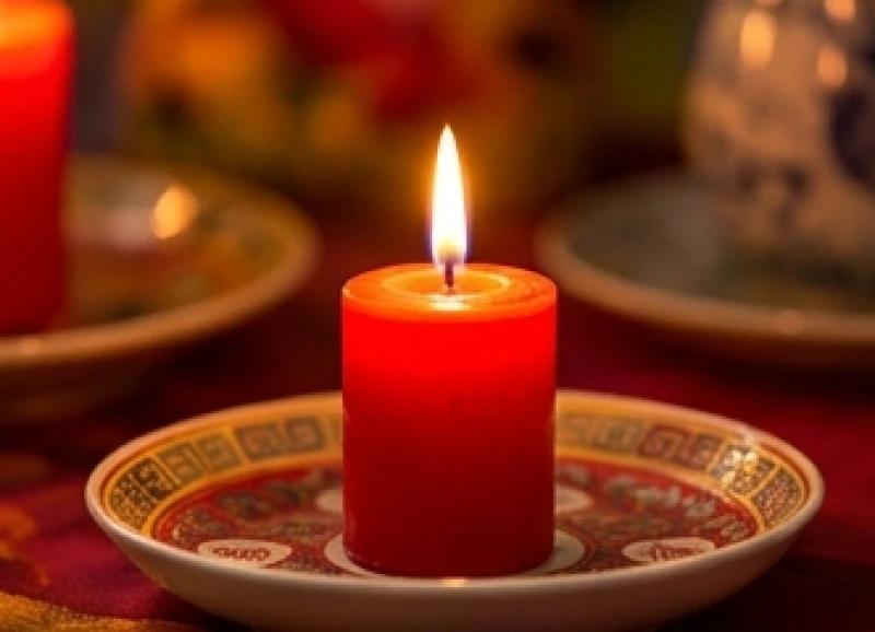 Nến đỏ đang cháy sáng lung linh trên khay gốm sứ tượng trưng cho năng lượng Hỏa vượng của năm Bính Ngọ